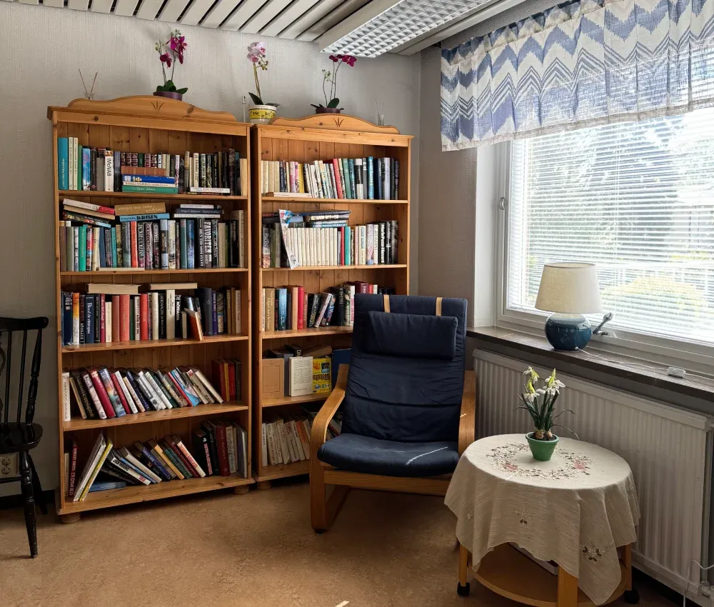 Läshörna med bokhyllor, fåtölj och bord vid fönstret