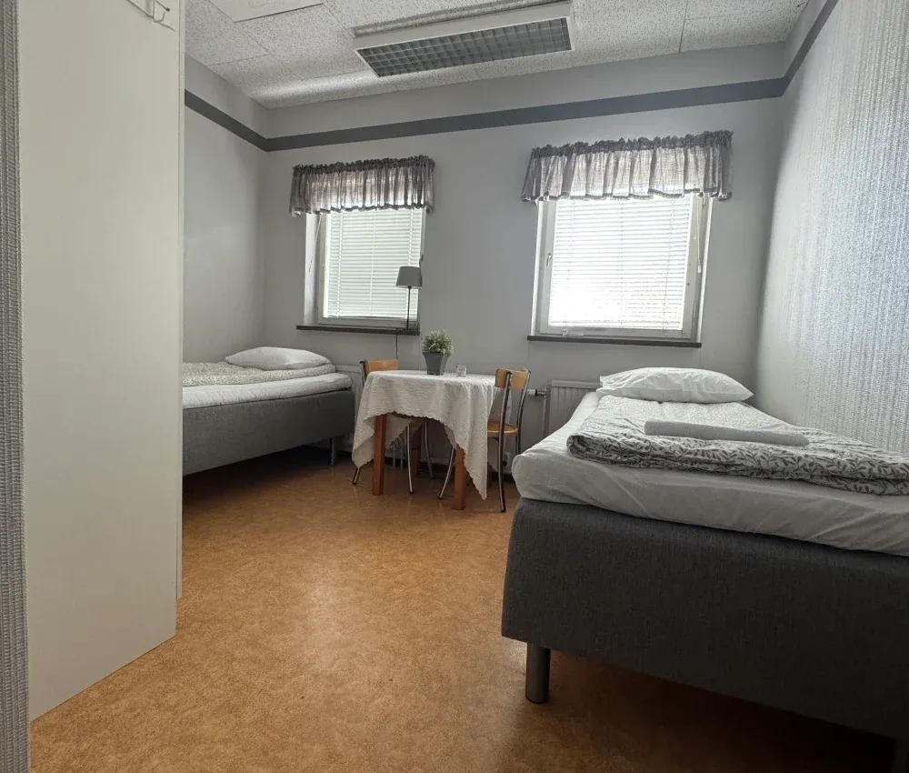 Rum 4 med två enkelsängar och ett bord mellan fönstren
